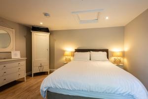 1 dormitorio con 1 cama blanca grande y 2 lámparas en Quiet Self contained Cottage near Delamere Forest en Cuddington