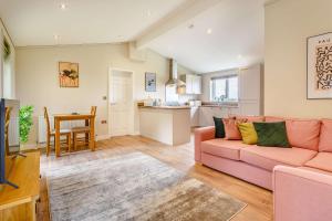 a living room with a pink couch and a kitchen at Duet Lodge in Kingham