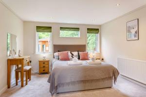 a bedroom with a bed with a desk and windows at Duet Lodge in Kingham