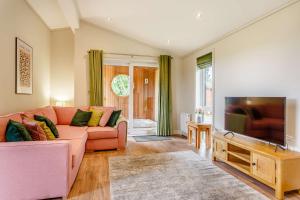 a living room with a pink couch and a flat screen tv at Duet Lodge in Kingham