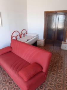 Sofá rojo en una habitación con cama en Appartamento Campomarino Lido lungo di mare, en Campomarino