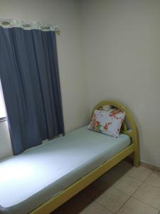 a small bed in a room with a blue curtain at CASA DA LÉIA in Caparaó Velho