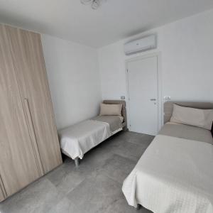 two beds in a room with white walls and concrete floors at La Pineta, 26 - 5 in Casarza Ligure