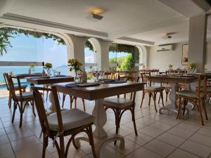 un comedor con mesas y sillas y el océano en Byblos Pousada, en Búzios