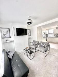 uma sala de estar com um sofá de couro preto e cadeiras em Gillingham 4 bed Guest House em Gillingham
