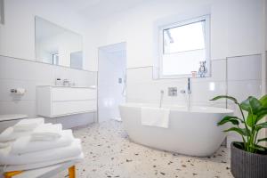 a white bathroom with a tub and a window at Hanse Villa - Apartment Hamburg in Lübeck +15 photos