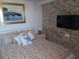 1 dormitorio con 1 cama y TV en una pared de ladrillo en Apartment Ena, en Stara Novalja