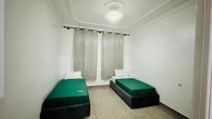 een kamer met een groen bed en een raam bij Grand appartement avec rooftop in Monte ʼArrouit