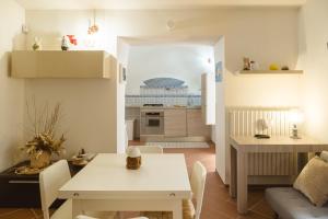 uma pequena cozinha e sala de estar com uma mesa branca e cadeiras em Trulli Minerva em Noci