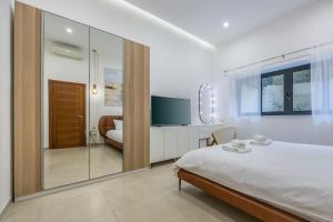 une chambre blanche avec un lit et une télévision dans l'établissement St. Julian's Urban Escape, à San Ġiljan