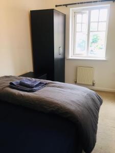 ein Schlafzimmer mit einem Bett mit einem schwarzen Schrank und einem Fenster in der Unterkunft Caroline Court House in Burton upon Trent