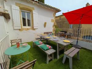 un patio avec une table, des chaises et un parasol rouge dans l'établissement Maison de Village 18ème Siècle Familiale 3 Chambres, à Mus