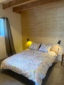 ein Schlafzimmer mit einem Bett mit einer Holzwand in der Unterkunft Gîte du Redondet 