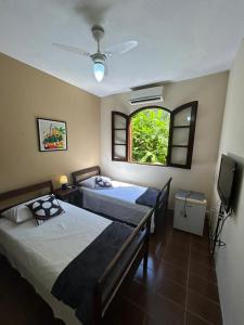 two beds in a room with a window at POUSADA RECANTO DA LADEIRA in Paraty