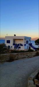 a white house with blue stairs in front of the ocean at Καραμπεικο in Piso Livadi