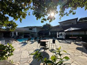 un patio con sillas, una mesa y una piscina en Pousada Corsario Buzios, en Búzios