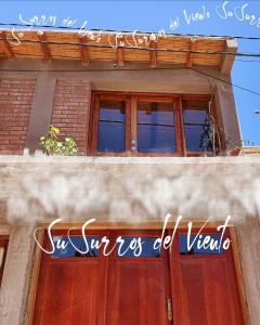 ein Gebäude mit zwei Fenstern und einer Holztür in der Unterkunft susurros del viento in Tilcara