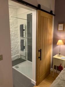 a shower with a glass door in a bedroom at Cosy Little Barn near Bath in Rode +9 photos