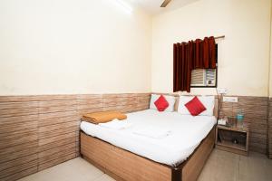 Habitación pequeña con cama con almohadas rojas en Hotel Sai Parikrama, en Bombay