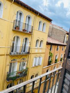 un edificio amarillo con ventanas y balcones junto a una valla en Apartamentos Zaragoza Coso, en Zaragoza