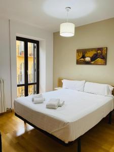 a large white bed in a room with a window at Apartamentos Zaragoza Coso in Zaragoza