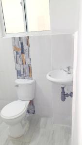 a white bathroom with a toilet and a sink at apartahotel Cartagena in Cartagena de Indias