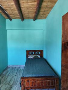 Cama en habitación con pared azul en susurros del viento en Tilcara
