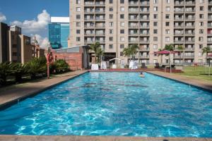 a large swimming pool in front of a large building at Sandton Lux, CBD, 2 Bedroom & 2 Ensuite, No Load shedding in Johannesburg