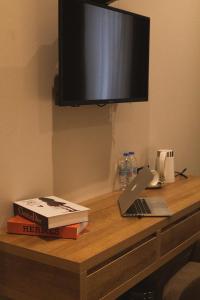 a desk with a television and a laptop and books at Central Hotel Kutaisi in Kutaisi