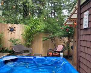 a hot tub in a backyard with chairs and a fence at Forest Sweet Retreat Hot Tub & Wood Fired Sauna in Ucluelet