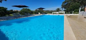 een groot blauw zwembad met twee parasols bij Quinta do Lagar - Rural Retreat by the Beach #6 in Albufeira