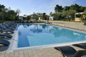 a large swimming pool with lounge chairs around it at Holiday Homes Ahil 7&8 in Pakoštane