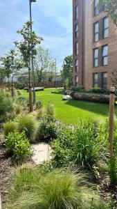 un giardino con erba e piante di fronte a un edificio di RomaVita Apartment near Heathrow a Hayes
