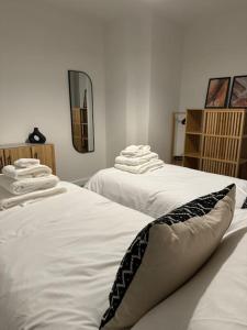 2 letti bianchi in una stanza con asciugamani di RomaVita Apartment near Heathrow a Hayes