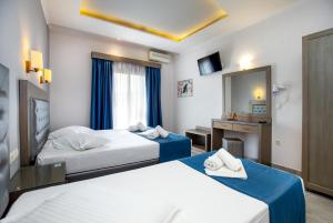 a hotel room with two beds and a mirror at Hotel Thetis in Limenas
