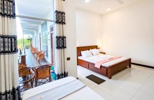 a hotel room with a bed and a balcony at The Amora in Arugam Bay