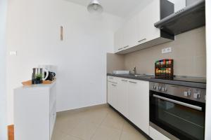 uma cozinha com armários brancos e um forno com placa de fogão em Apartman Punta Sole em Zadar