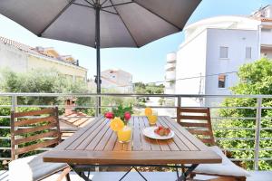 un tavolo in legno su un balcone con ombrellone di Apartman Punta Sole a Zara (Zadar)