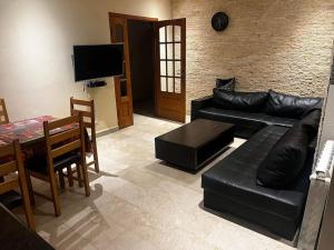 ein Wohnzimmer mit einem schwarzen Ledersofa und einem Tisch in der Unterkunft Magnifique villa avec piscine 