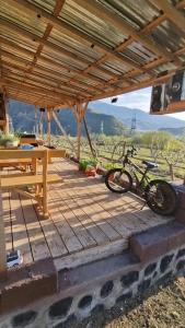 - un vélo garé sur une terrasse couverte en bois avec une table dans l'établissement GreenField GH, à Yeghegnadzor