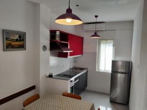 a kitchen with red cabinets and a table and a refrigerator at Apartments Vili in Umag +8 photos