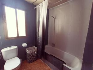 a bathroom with a toilet and a tub and a window at Céntrico, con terraza y barbacoa - by Aloha Palma in Águilas