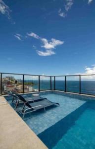 a swimming pool with a view of the ocean at Barra, compacto, novo e aconchegante in Salvador