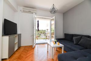 uma sala de estar com um sofá e uma televisão em Apartman Punta Sole em Zadar