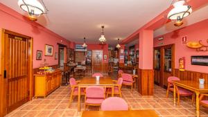 ein Restaurant mit rosa Wänden, Holztischen und Stühlen in der Unterkunft La Fragua II in Trevélez