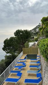 een groep blauwe ligstoelen aan een muur bij Hotel Torre Saracena in Praiano