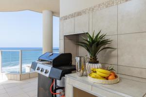 a kitchen with a stove with bananas and a bowl of fruit at Santorini 401A in Margate