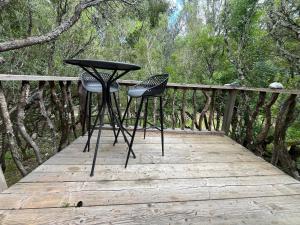 2 Stühle und ein Tisch auf einer Holzterrasse in der Unterkunft Petit chalet en pleine nature avec accès rivière in Venaco