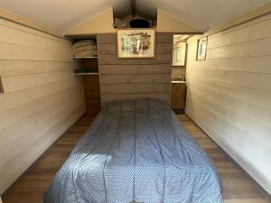 Bett in der Mitte eines Zimmers mit Holzwänden in der Unterkunft Petit chalet en pleine nature avec accès rivière in Venaco