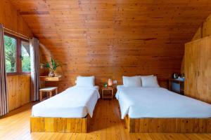 two beds in a room with wooden walls at Chay Lap Farmstay Phong Nha in Ðá Lòn